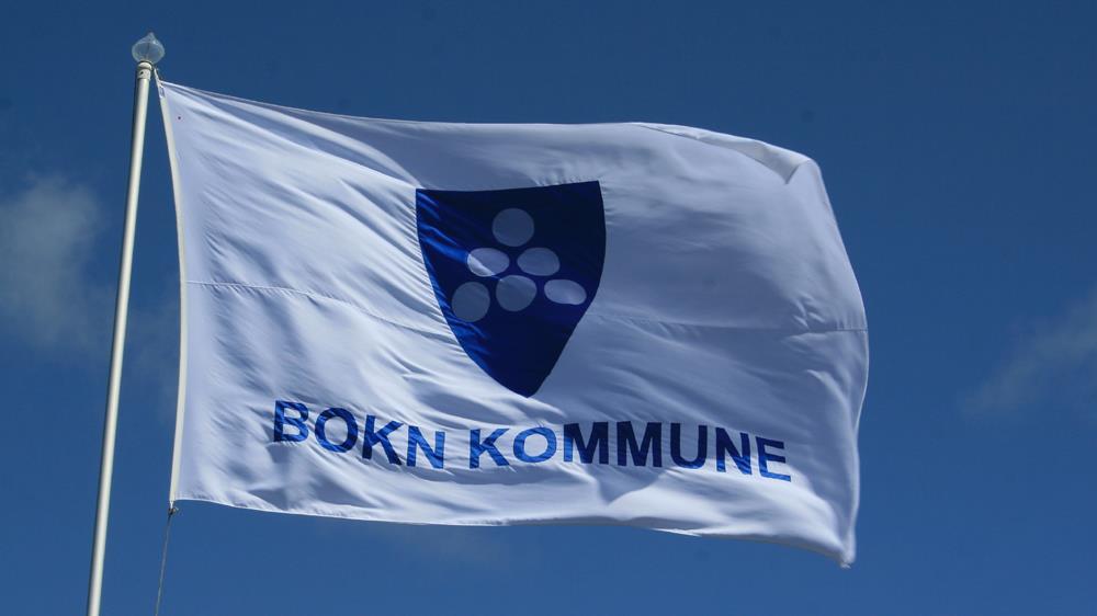 Bildet viser eit kvitt flag med kommunevåpenet og teksten Bokn kommune på. - Klikk for stort bilete